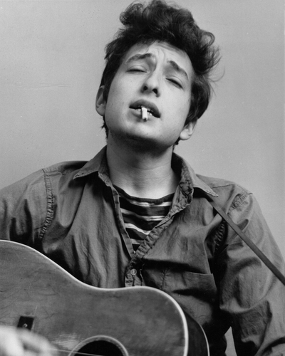 Bob Dylan plays acoustic guitar and smokes a cigarette in this headshot from September 1962 in New York City